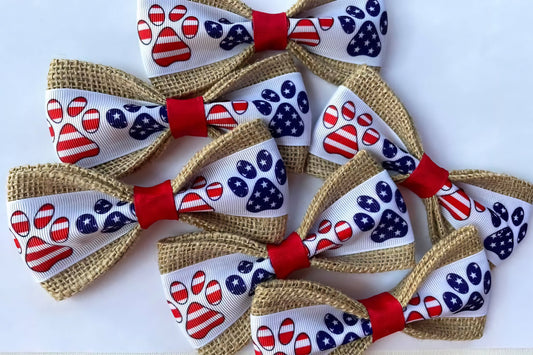 Set of dog bows with American flag and paw print patterns on a white background.|Ensemble de nœuds pour chiens avec des motifs de drapeau américain et d'empreintes de pattes sur fond blanc.