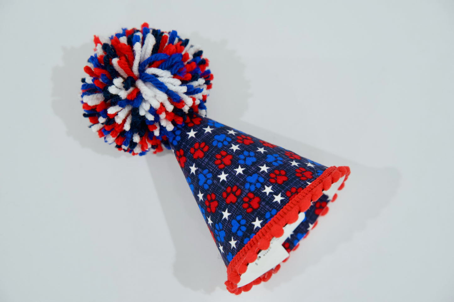 Chapeau de fête pour animal, avec un motif rouge, blanc et bleu sur fond gris clair.