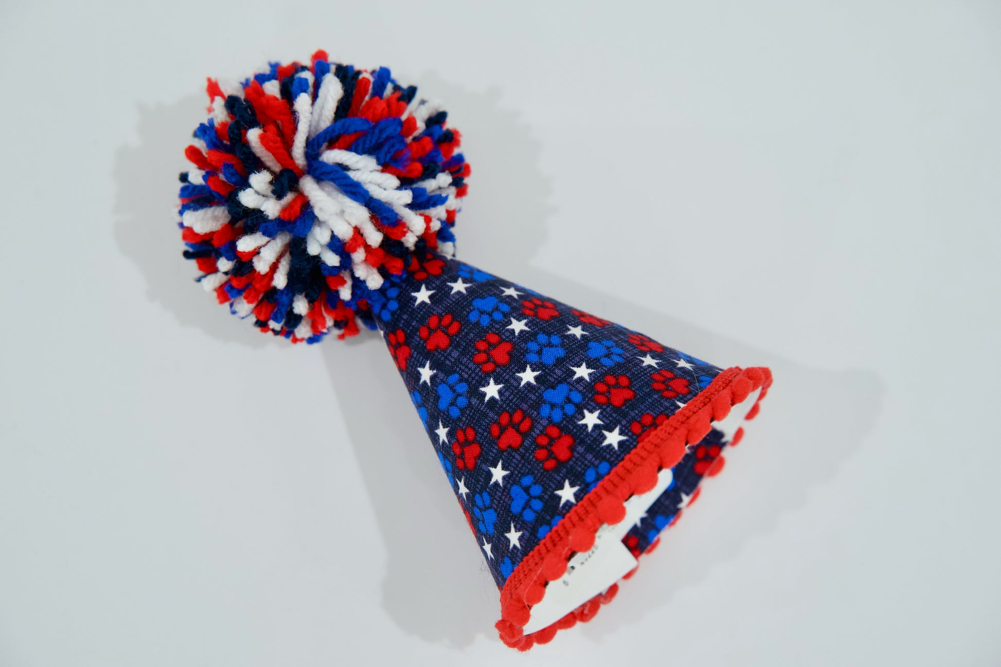 Chapeau de fête pour animal, avec un motif rouge, blanc et bleu sur fond gris clair.