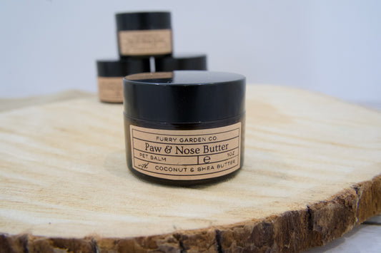 Jar of pet balm Paw & Nose Butter on a wooden surface.|Pot de baume pour animaux Beurre pour pattes & museau sur une surface en bois.