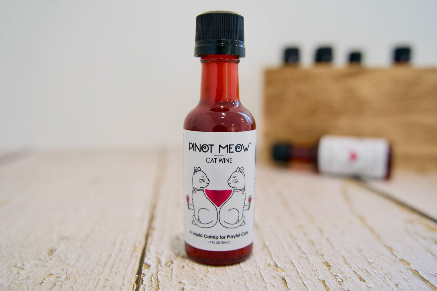 Bouteille de vin pour chats Pinot Meow sur une surface en bois, avec un arrière-plan flou.
