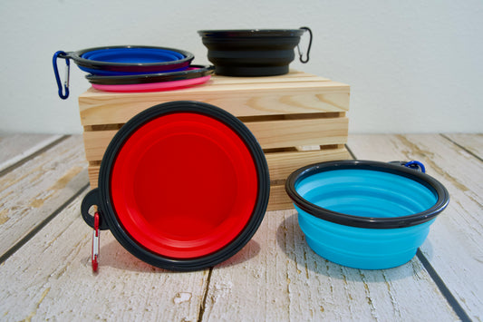 Collapsible pet bowls in various colors on a wooden surface.|Gamelles pliables pour animaux de compagnie, de différentes couleurs, sur une surface en bois.