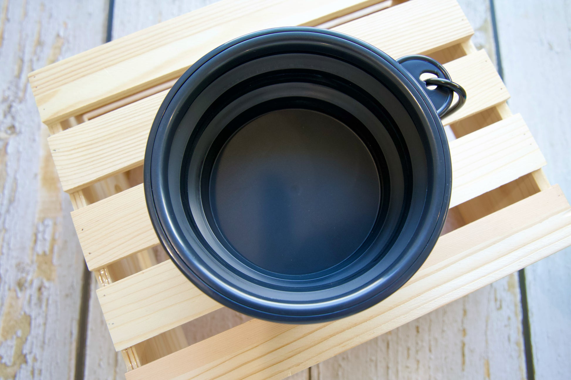 Mug pour chien de voyage pliable noir sur une surface en bois.