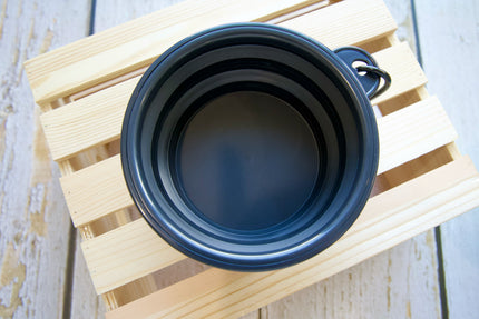 Mug pour chien de voyage pliable noir sur une surface en bois.