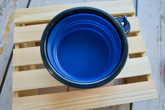 Blue pet collapsible travel mug on a wooden surface.|Mug de voyage pliable bleu pour animaux, posé sur une surface en bois.