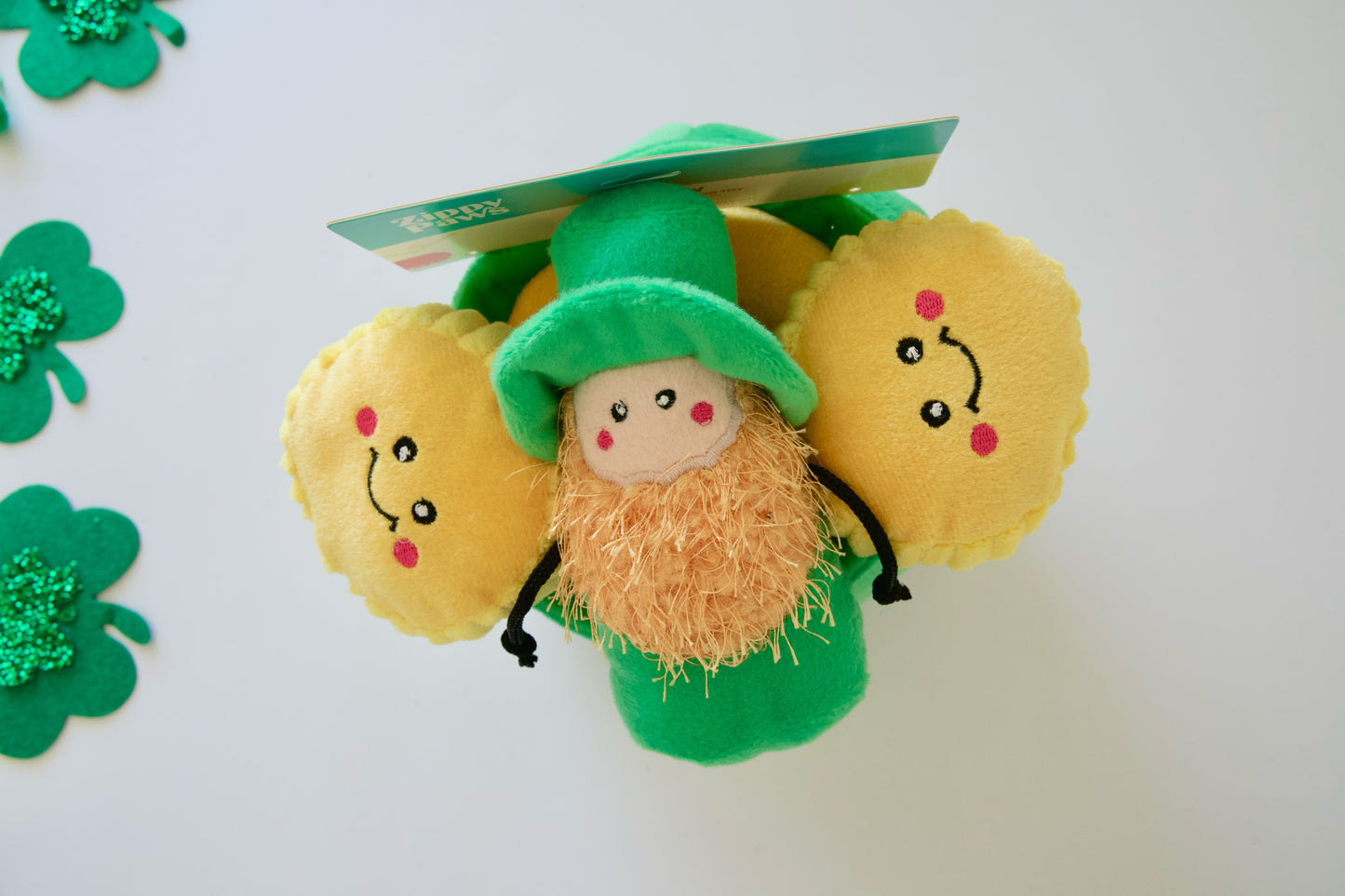 Top view of the dog plush toy resembling a leprechaun with gold coins on a white background.