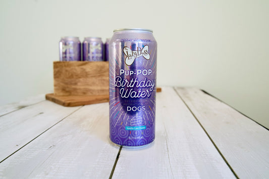 Can of Pup Pop Birthday Water for dogs on a wooden surface.|Canette de boisson gazeuse pour chiens Pup Pop Birthday Water sur une surface en bois.