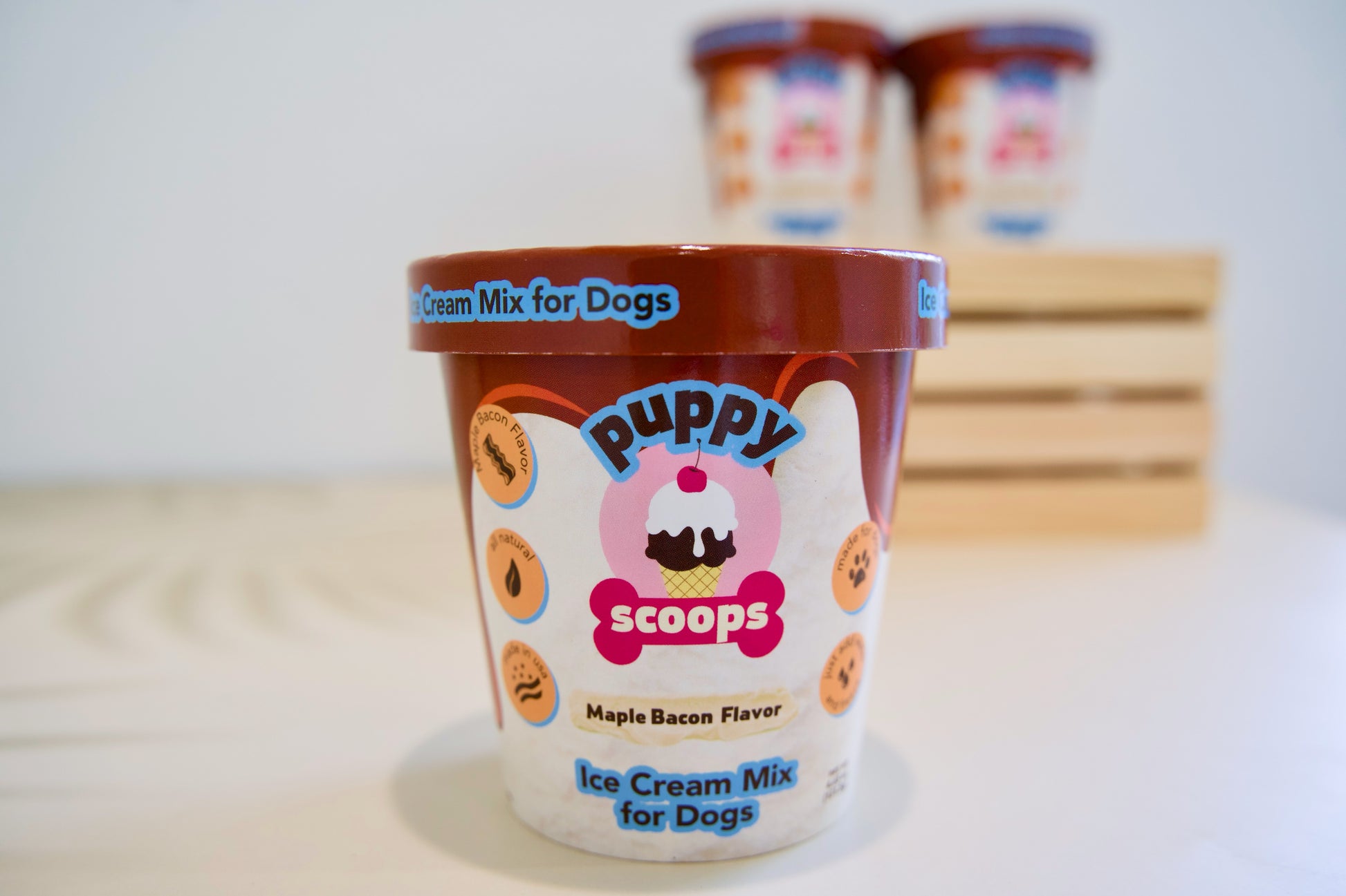 Préparation pour crème au bacon à l'érable pour chiens Puppy Scoops, dans un pot posé sur une surface blanche.