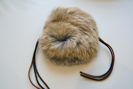 Fur pom-pom cat toy with leather strap on a white background.