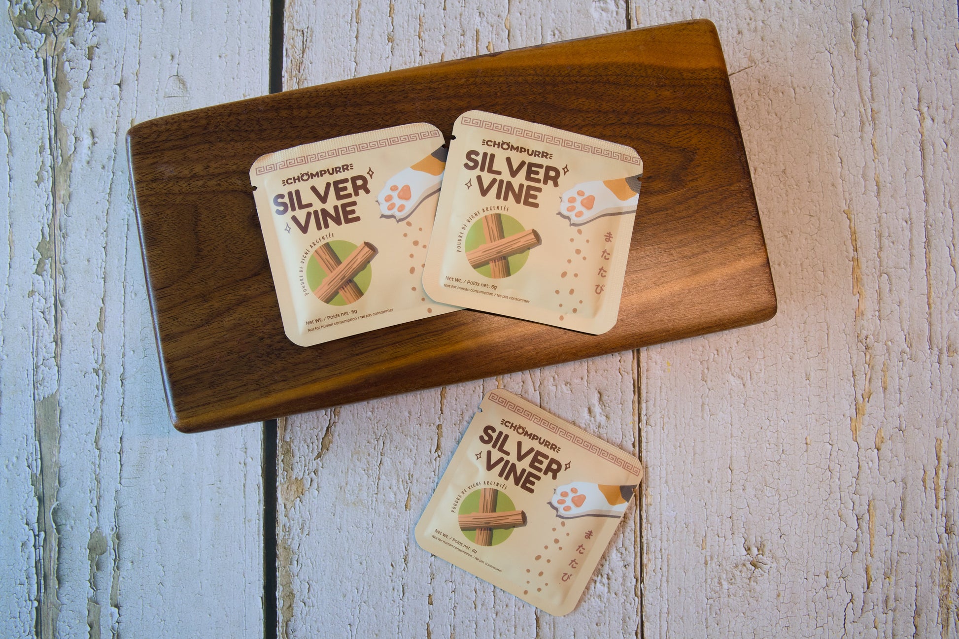 Trois petits sachets de jouets pour chats en Silvervine posés sur une planche en bois sombre.