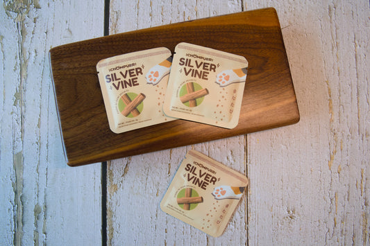 Three small pouches of Silvervine cat toys on a dark wooden board.|Trois petits sachets de jouets pour chats en Silvervine posés sur une planche en bois sombre.