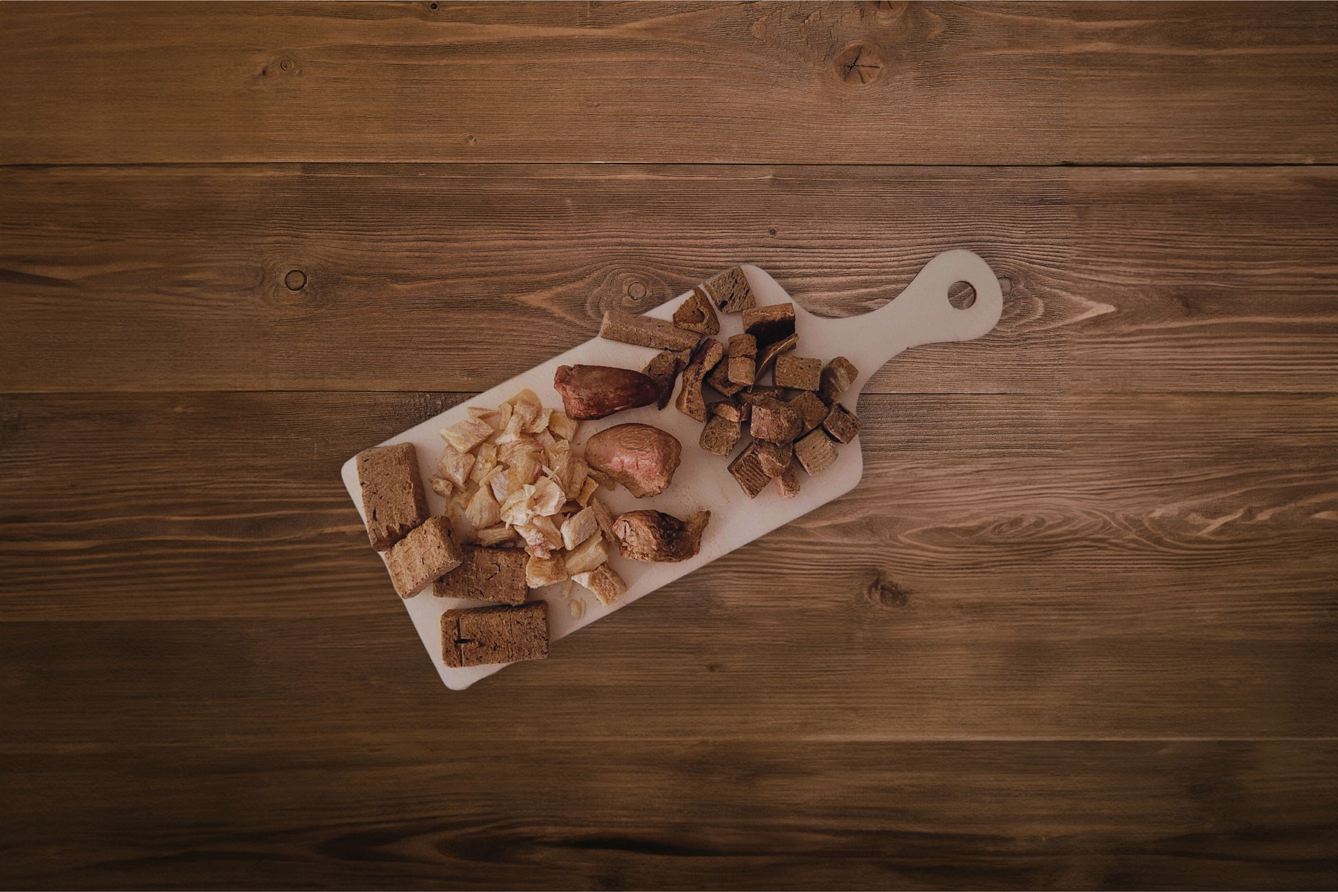 Un assortiment de friandises lyophilisées pour chiens, présenté sur un plateau de type « charcuterie » au format snack.