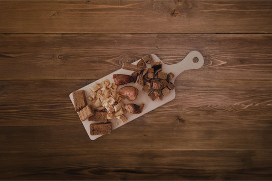 Assorted freeze-dried treats for dogs on a snack format charcuterie board.|Un assortiment de friandises lyophilisées pour chiens, présenté sur un plateau de type « charcuterie » au format snack.