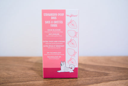 Back of the pink packaging of strawberry poop bags on a wooden surface with a white background.