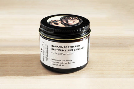 Pot de dentifrice pour chien à la saveur de banane sur une surface en bois.