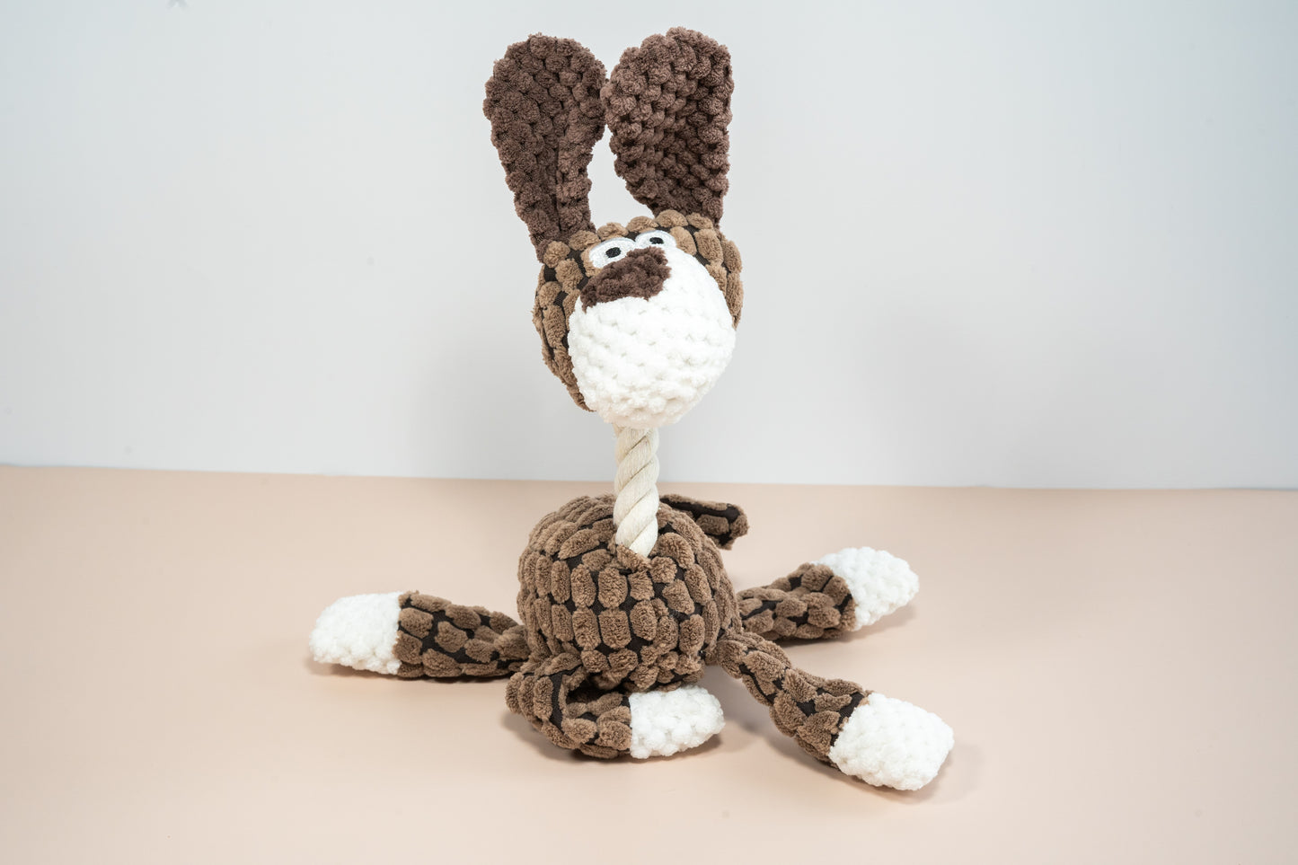 Plush dog toy in brown dog shaped with rope neck.