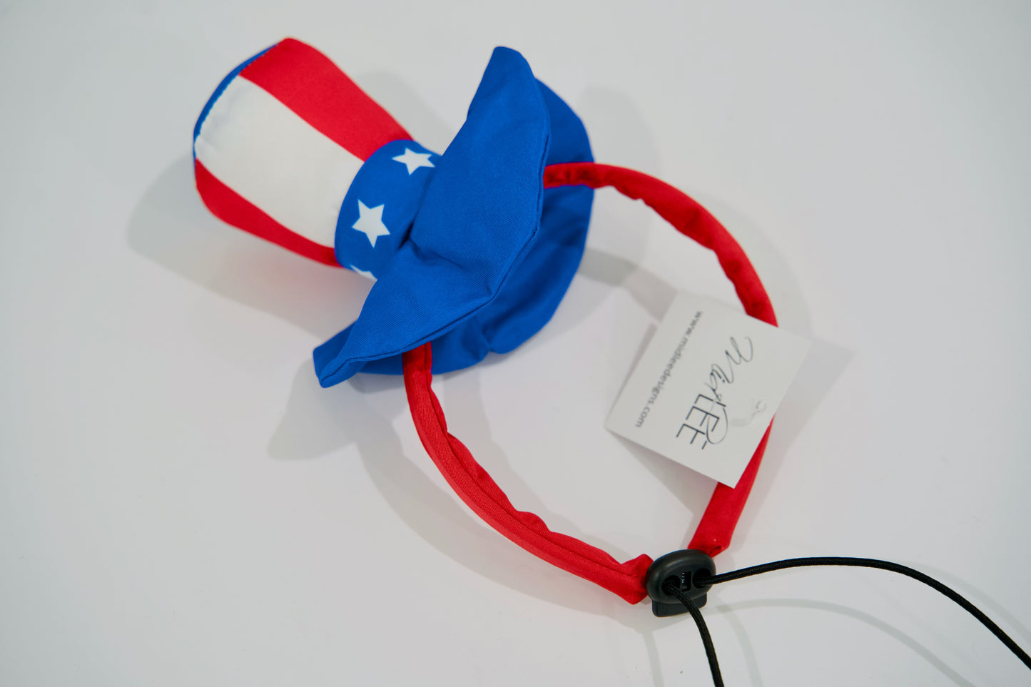 Serre-tête pour chien rouge, blanc et bleu avec un nœud, sur fond blanc.