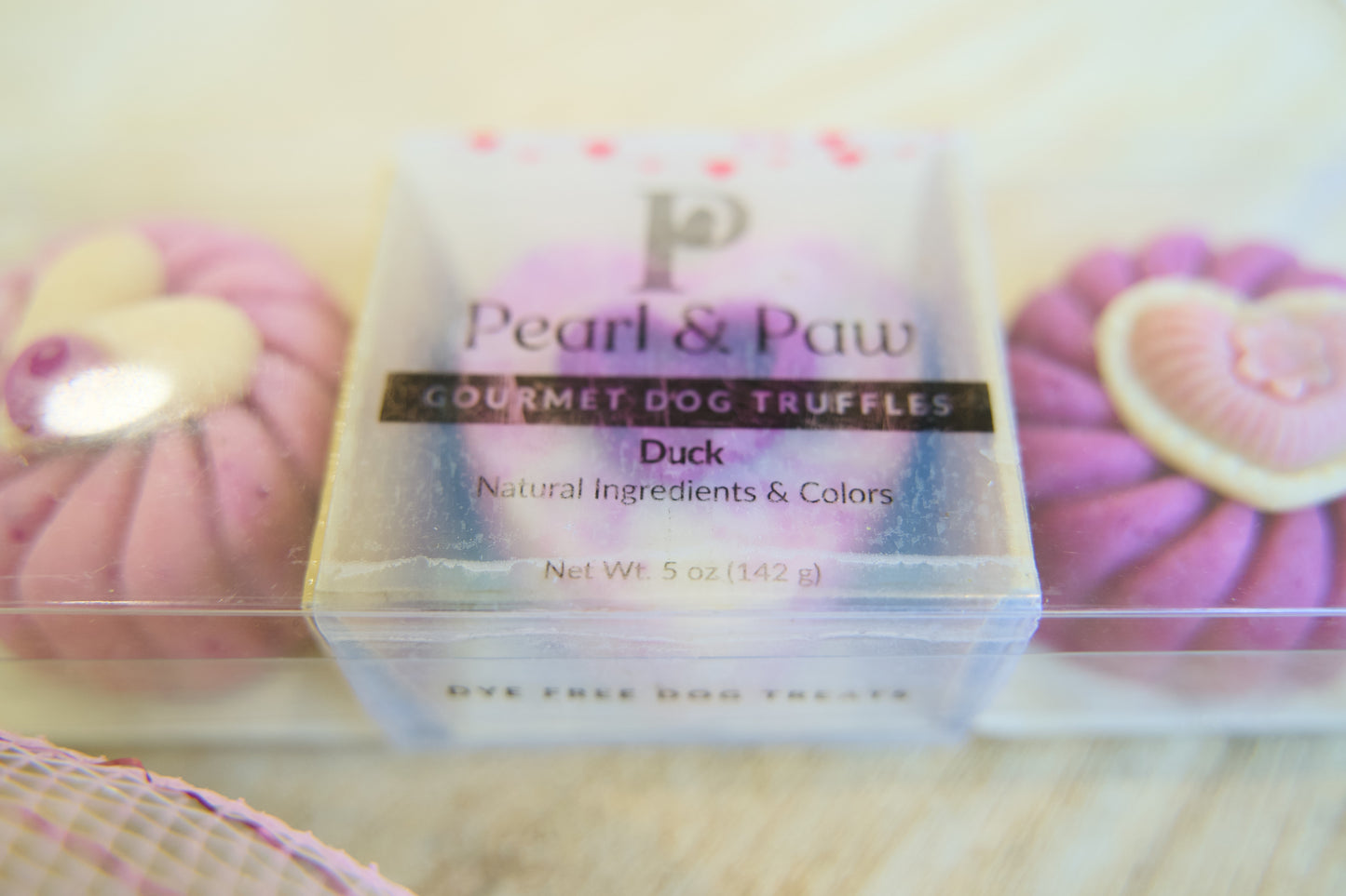 Pearl & Paw gourmet dog truffles packaging with pink truffles in the background.