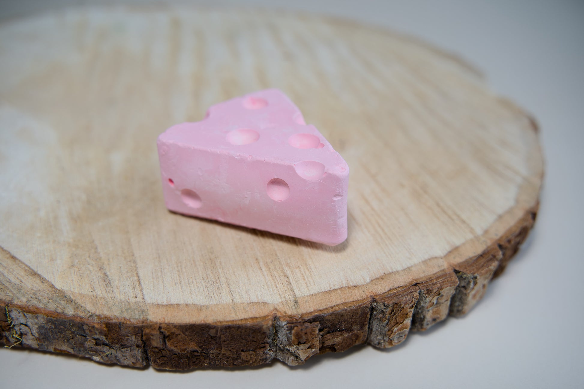 Pink cheese-shaped volcanic stone for small rodents to chew on.|Pierre volcanique en forme de fromage de couleur rose à mâcher pour les petits rongeurs.