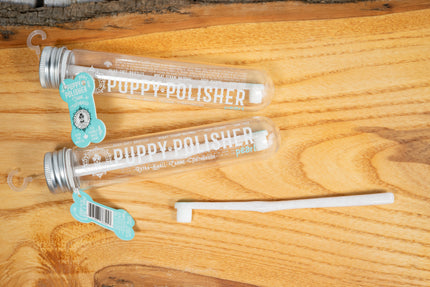Brosse à dents pour très petit chien dans son contenant posé sur une planche de bois.