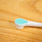 Close-up view of the tongue scraper behind the toothbrush head for extra small dogs.