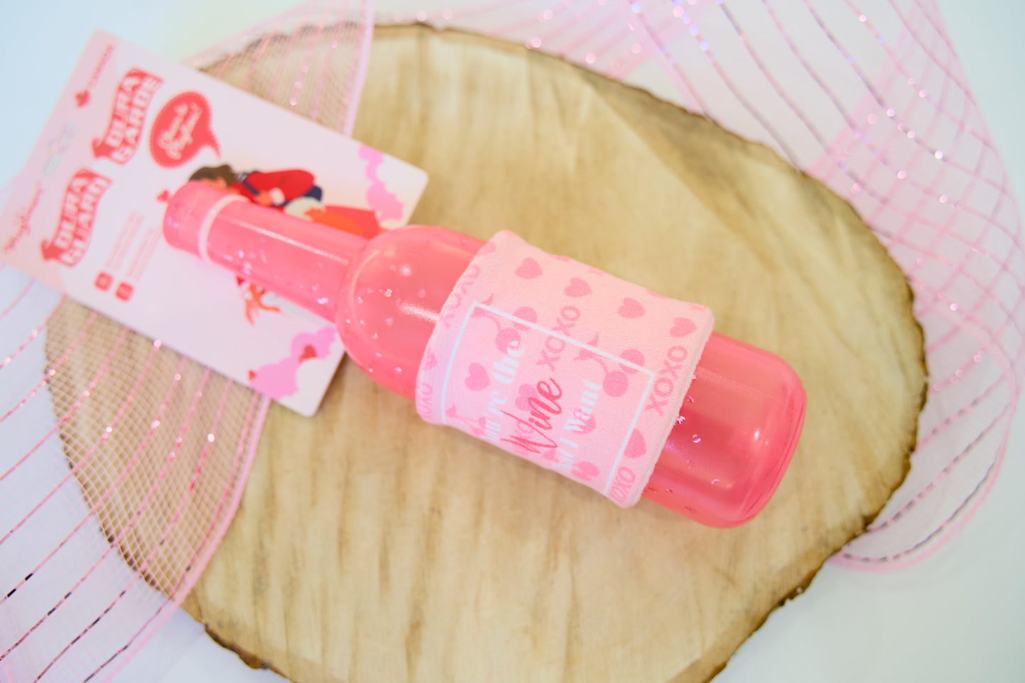 Pink wine bottle for dogs on a wooden surface.