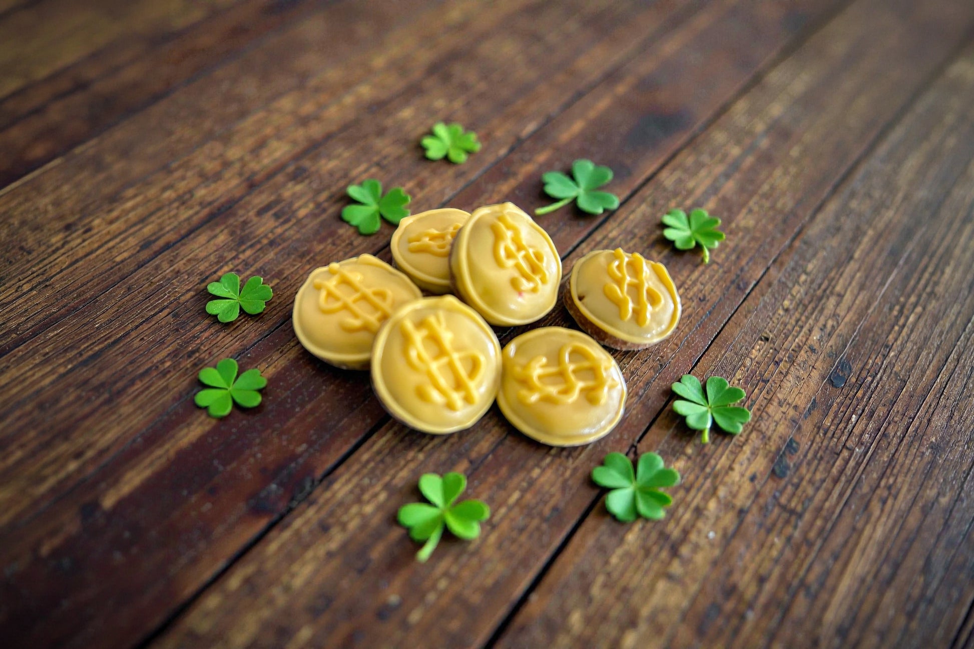 Mini gold coins shaped dog treats with dollar signs surrounded by clover leaves.